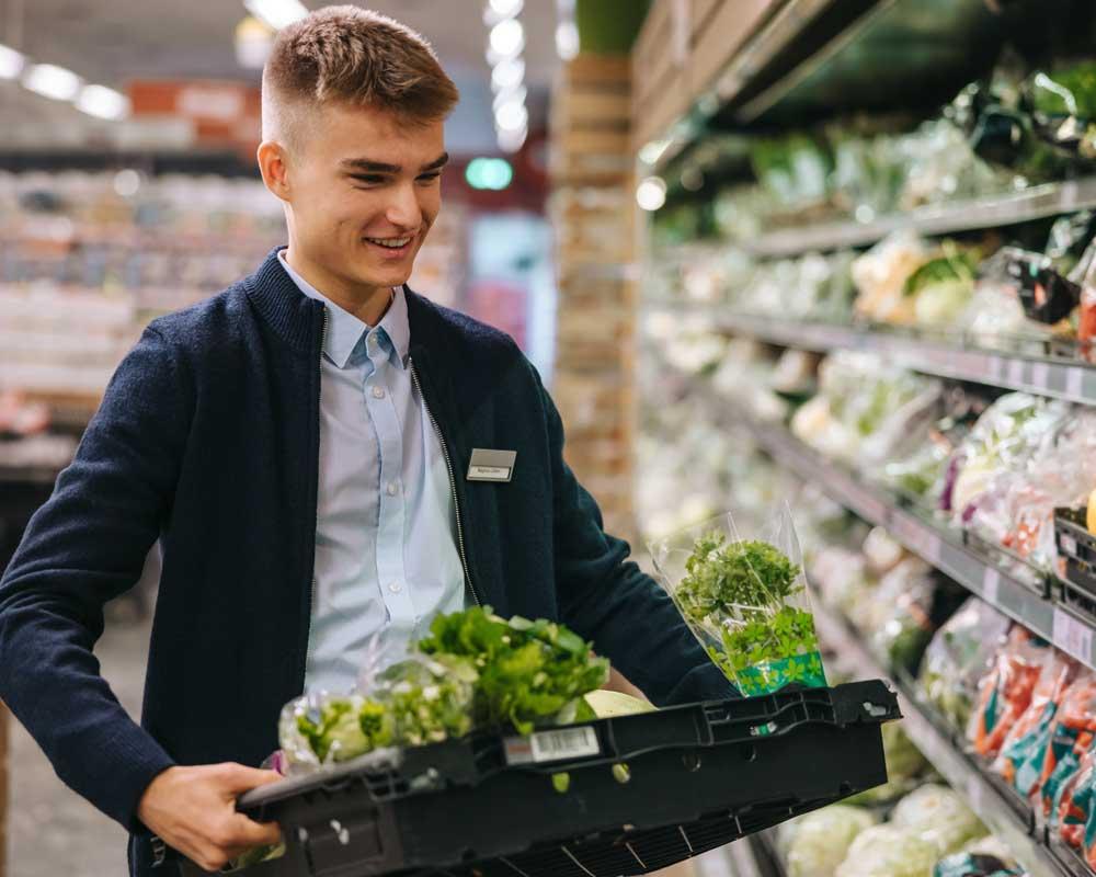Supermarket worker restocking vegetables
