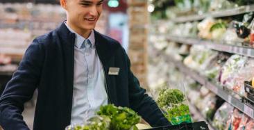 Supermarket worker restocking vegetables