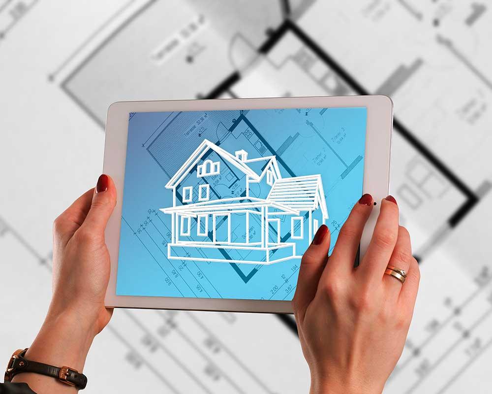 Hands holding tablet over building plans