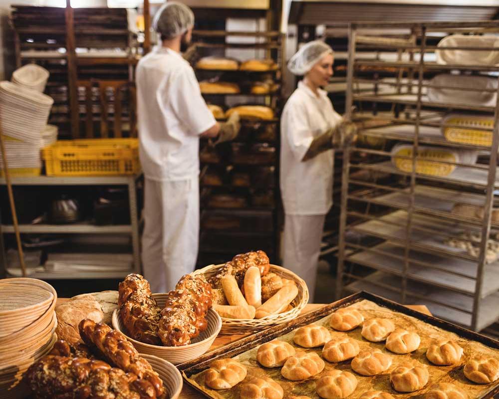 Bakers working in a bakery with loaves of bread