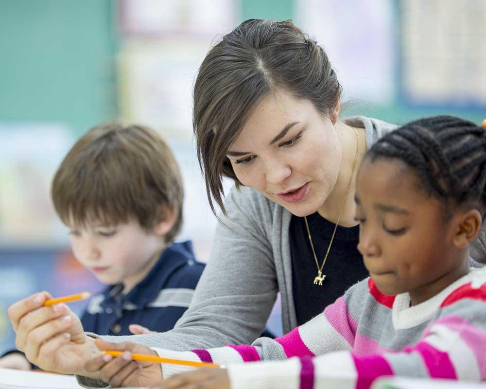 Teaching assistant sitting with 2 children